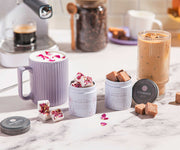 Coffeeshop setting with coffee cups, a coffee machine, and various treats on a marble surface.